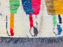 Load image into Gallery viewer, A multi-colored Berber rug with a spectrum of vibrant hues and bold geometric designs spread across its surface.
