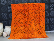 Load image into Gallery viewer, Handmade orange Moroccan wool rug featuring bold black geometric patterns, perfect for boho living rooms and modern home decor.


