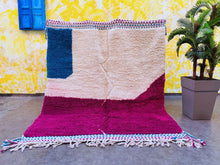 Load image into Gallery viewer, Vibrantly colored Moroccan rug laid flat with a backdrop of a yellow wall and a blue window, featuring intricate geometric patterns.
