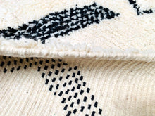 Load image into Gallery viewer, Close-up of the soft, creamy white edge of a Beni Ourain rug with contrasting black dotted patterns, highlighting the handwoven craftsmanship.
