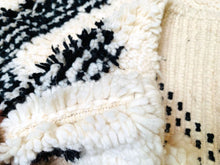 Load image into Gallery viewer, Textural detail of a Beni Ourain Moroccan rug featuring plush wool with an intricate black geometric design, exemplifying artisanal weaving techniques.
