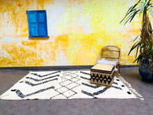 Load image into Gallery viewer, Modern and chic living space highlighted by a luxurious Beni Ourain Moroccan rug adorned with distinctive black abstract designs, paired with boho-style furniture
