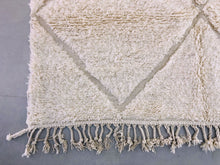 Load image into Gallery viewer, Corner section of a Beni Ourain rug highlighting the geometric diamond patterns and tassel fringe.
