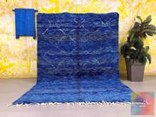 Load image into Gallery viewer, Full view of a handcrafted blue Moroccan Berber rug against a vibrant, abstract yellow wall with a blue window accent
