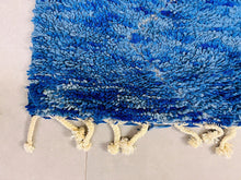 Load image into Gallery viewer, An angled view of a luxurious blue Berber rug with patterned design and fringed edges.
