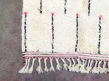 Load image into Gallery viewer, An artisanal Moroccan wool rug, with a focus on the fringed edge and the symmetrical pattern that makes it a centerpiece for any room.
