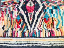 Load image into Gallery viewer, A Moroccan wool rug displayed in a living space, with the intricate design and fringe detailing clearly visible
