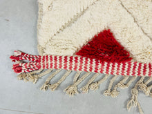 Load image into Gallery viewer, Hand-tied fringe detail on a red and white Moroccan Beni Ourain rug, embodying the authentic beauty of Berber textile art.
