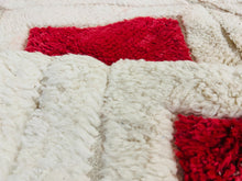 Load image into Gallery viewer, Detailed view of a plush Moroccan Berber Beni Ourain rug with a bold red diamond pattern set against a creamy white background, highlighting the luxurious pile and rich color contrast.
