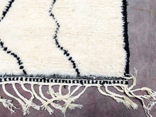 Load image into Gallery viewer, Close-up of a cream and black Moroccan wool rug with detailed fringe and geometric patterns
