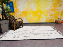 Load image into Gallery viewer, Luxurious handwoven Moroccan rug laid out in a spacious room, with lush fringe detailing
