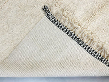 Load image into Gallery viewer, Detail of the edge stitching and fringe on a handcrafted Moroccan wool rug.
